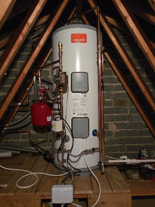 Hot water cylinder with connected pipework in a loft